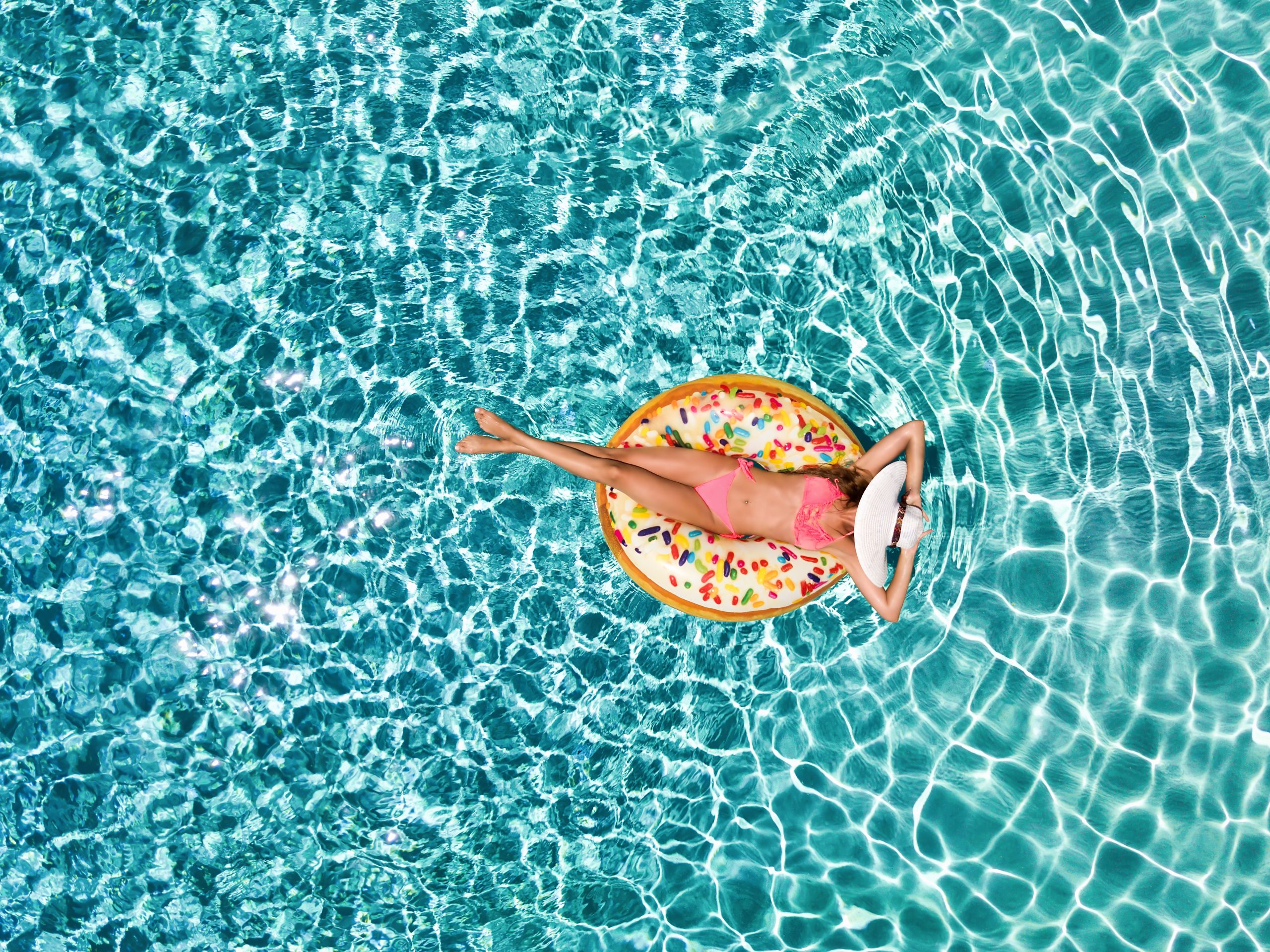 Eine Dame liegt im Schwimmreifen und lässt sich im Pool treiben.